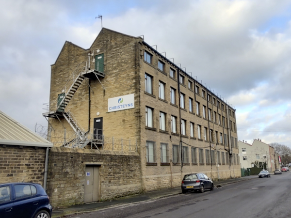 Photograph: Izzie Smith | Victoria Mill of Rutland St, now home to Christeyns UK Ltd (previously Oils and Soaps Ltd, providing chemicals to textile mills in 1980s). This building has been repurposed into offices. A coloured photograph of Christeyns UK Ltd Building and street. Photograph: Izzie Smith